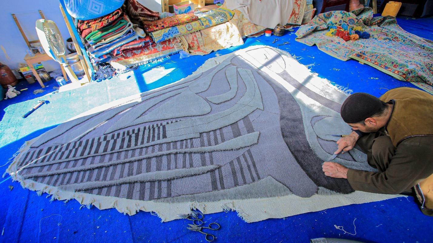 a man weaving a carpet 